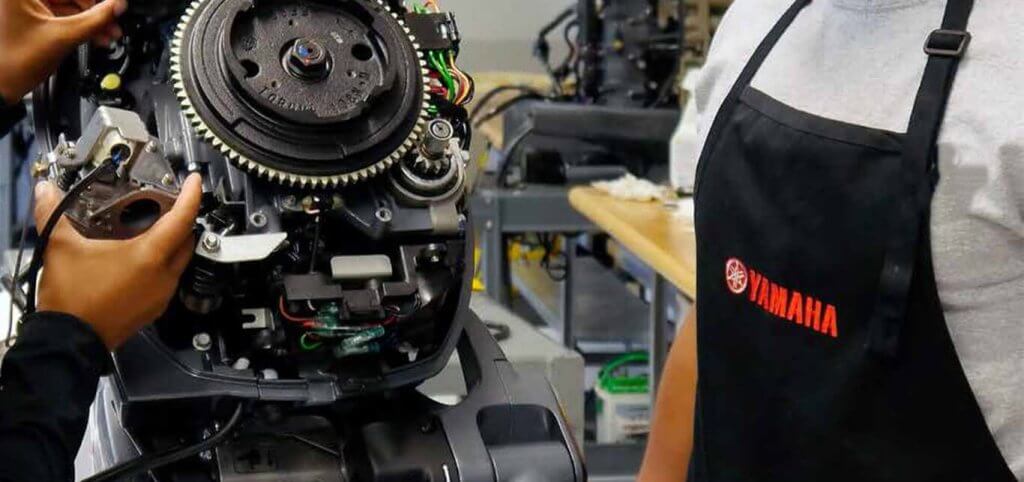 Serviser u Yamaha pregači rastavlja rasklopljeni vanbrodski motor sa zamašnjakom u ovlaštenoj radionici.