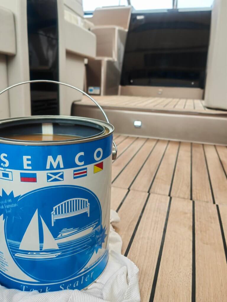 Limenka SEMCO Teak Sealer premaza na svijetloj očišćenoj teak palubi jahte tijekom održavanja teaka.